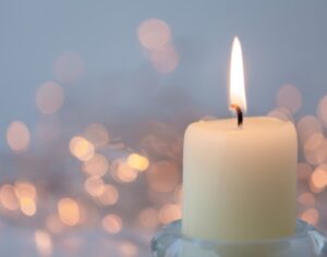 Kerze vor glitzerndem, leuchtenden Hintergrund