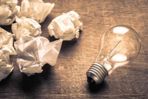 Zerknüllte Blätter und Glühlampe auf Tisch